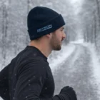 Man jogging on snowy path wearing Seattle Polar Fleece Beanie, side profile view.