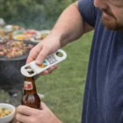 Man uses Vette Bottle Openers Small to open beer at an outdoor barbecue.