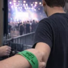 Person wearing Event Wrist Bands enters a crowded outdoor classic car show.