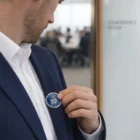 Man in suit attaching Lapiz Lapel Pins Round Large near conference room.