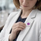 Woman in a white blazer attaching a Lapiz Lapel Pins Square Large with a purple flower design.