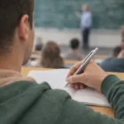 Student takes notes with Universe Logo Pens while teacher writes on chalkboard.