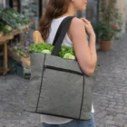 Woman carries a Luxire Tote Bag with veggies and a baguette on a cobblestone street.