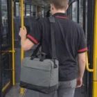 Person with a gray Woven Personalised Satchel Bag stands on a bus holding a yellow pole.
