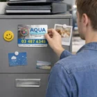 Person placing a flyer on a gray filing cabinet with Event Branded Rectangle Fridge Magnets 7cm.