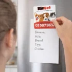 Someone puts a Square Fridge Magnet with a pet theme above their grocery list.