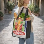 A woman carries a Harriet Tote Bag with produce and a baguette on a cobblestone street.