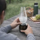Person holding an Outdoor Personalised Led Lamp on a picnic table with food and drinks.