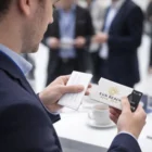 Man holding a Sun Beach business card and Anti Theft Rfid Card Protectors at an event.