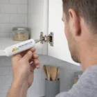 Handyman using Handyman Mini Screwdriver Sets to adjust a cabinet hinge in the kitchen.