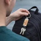 Person attaching Theon Keyrings, keys, and a lock to a black backpack.