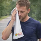 Man using Sports Cooling Towel outdoors; Social Heart Foundation logo visible on the towel.