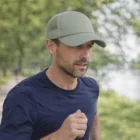 Man in a Randolph Logo Branded Mesh Trucker Cap and navy shirt jogging on a tree-lined path.