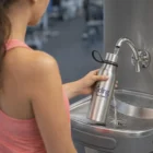 Woman fills a David Vacuum Bottle at a gym water fountain.