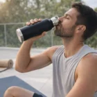 Man in workout clothes drinks outdoors from a 750Ml Stainless Steel Vacuum Bottle.