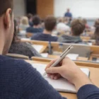 Student takes notes in a lecture hall with a Lamy Logo Brushed Stainless Steel Pen.
