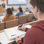 Student taking notes in a lecture hall with Blank Page Notebooks.