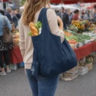 Person with a blue Pocket Folding Shopper Bag filled with groceries at an outdoor market.