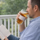 Man reading a book and sipping tea from Eco Double Wall Glass Cups on a green porch.