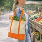 Woman with Reusable Natural Style Event Bag holding vegetables at an outdoor market.