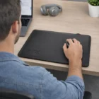 Man working on laptop using Zeta Wireless Charging Mouse Mat, headphones and plant nearby.