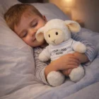 Young child sleeping in bed, hugging a Fluffy Lamb Plush Toy with a customizable shirt.