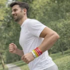 Man jogging in Stuttgart, wearing Stuttgart Xtra Silicone Wrist Bands, trees in the background.