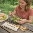 Woman using Bamboo Eco Friendly Cutlery Sets while eating salad outdoors at a picnic table.