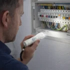 A person inspects an open electrical panel using a Steersman Customised Torch.