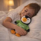 Smiling child hugs Penguin Custom Branded Plush Toys in a green shirt—ideal for promotions.