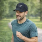 Man jogging in a park wearing a blue shirt and an Abdiel Cap With Patches.