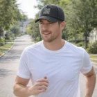 Man jogging outdoors in a white tee and Soft And Stretchy Sports Cap with "Your Logo Here.