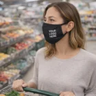Woman in a grocery store wearing a black reusable cotton face mask (unbranded).