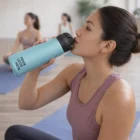 Woman in workout clothes sips from a Personalised Camelbak 600Ml Vacuum Bottle at yoga class.