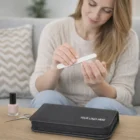 Woman filing nails with Swiss Peak Manicure Set and a custom logo pouch on the table.
