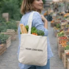 Woman at market with Dudley Shoulder Tote Bag filled with veggies, Your Logo Here shown.