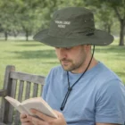 Man wearing Rushcliffe Wide Brim Hat reading on a bench in Rushcliffe park.