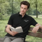 Man on a bench reading, wearing a black Sols Summer Ii Mens Polo with Your Logo Here.