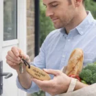 Man holding groceries and door keys with Natural Cork Keyrings, about to unlock the door.