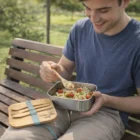 Smiling man eating salad on a park bench with reusable cutlery and Metal Lunch Boxes.