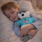A child sleeps in bed, cuddling a Seal Custom Plush Toy and wearing a blue Berry Blend shirt.
