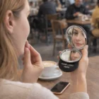 Woman with Messina Compact Mirror at café table, YOUR LOGO HERE on the mirror.