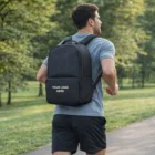 Man jogging in park with a gray shirt and a Vale Gym Bags backpack featuring Your Logo Here.