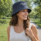 Woman in a tank top and Classic Denim Bucket Hat labeled YOUR LOGO HERE stands on a park path.