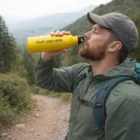 Man drinking from an 800ml Harrow Branded Bottle labeled "Your Logo Here" on a forest trail.