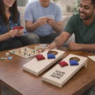Three people enjoy Mini Cornhole Games while playing cards at a wooden table.