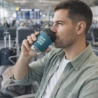 Man enjoys coffee in a Stellar Cups Maple 350Ml with custom logo at the airport terminal.