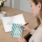 Woman writing a Milton Personalised Greeting Cards A5 at a wooden table with coffee nearby.