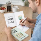 Man writing a Milton Custom Greeting Cards A6 at the kitchen table with coffee and strawberries.