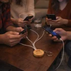 Four people use Laval Charging Cable Key Rings - Round on a coffee table multi-charger.